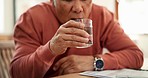 Drinking water, senior man and Parkinson or tremor with trembling hands at table in living room. Sick, elderly person and glass with neurology, muscle or shaking illness in lounge of retirement home