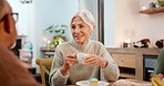 Tea party, elderly friends and people chatting in a retirement home together for bonding in the morning. Smile, drinking and a group of happy seniors talking in the living room of an apartment