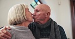 Kiss, elderly couple and coffee in home, conversation and bonding together in morning in winter. Love, senior man and woman with tea cup, drink and healthy relationship, connection or hug for romance