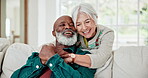 Senior couple, talking and hug on sofa with love, care and support in retirement together with happiness. Old people, relax and smile with embrace in home, living room or conversation in lounge