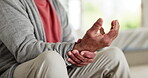 Hands, wrist pain or fibromyalgia with a senior person closeup in the living room of a retirement home. Medical, massage or osteoporosis and an elderly adult with a joint injury or arthritis disease