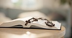 Bible, open and rosary on table for religion, worship or prayer for hope, spiritual or guidance in home. Closeup, holy and book for faith, reading or scripture for study with understanding of God