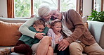 Happy, love and children hugging grandparents on a sofa in the living room at modern home. Smile, bonding and young kids embracing senior man and woman in retirement with care in the lounge of house.