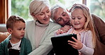 Happy, tablet and children with grandparents on a sofa watching a movie in the living room at home. Smile, digital technology and kids with grandmother and grandfather in retirement at modern house.