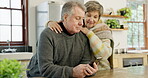 Phone, hug and a senior couple in the kitchen of their home together for communication or retirement. Love, smile or happy with an elderly man and woman browsing a social media app on a mobile