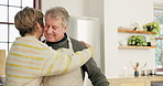 Happy, hugging and senior couple in the kitchen cooking a meal for dinner, lunch and supper. Smile, care and elderly man and woman in retirement embracing for romance in modern home together.