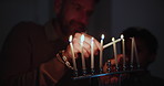 Jewish, holiday and a family lighting candles together in their home for Hanukkah celebration. Culture, religion or tradition with a father and son closeup in the dark for their faith or belief