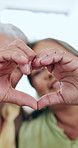 Elderly couple, heart and hands for love in home for care, kindness and bonding together. Closeup of man, woman and romance sign, peace emoji or connection, support or commitment, marriage and trust