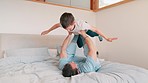 Bed, airplane and father with son, relax and happiness with energy, playing and cheerful. Home, bedroom and dad with boy, freedom and flying with support, family and love with game, smile and balance