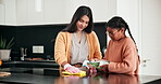 Mother, daughter or child cleaning house or kitchen with spray for learning, germs and bacteria for clean home. Woman teaching young girl to wipe surface with cloth to help with housework chores 