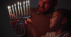 Jewish, tradition and a family lighting candles together in their home for Hanukkah celebration. Culture, religion or holiday with a father and daughter closeup in the dark for their faith or belief