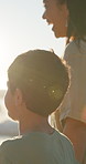 Asian family, beach and a mother walking with her son by the ocean or sea for love and bonding at sunset. Face, smile and a happy young woman with her boy child on the coast for holiday or vacation