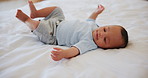 Sweet, cute and boy baby on a bed playing in nursery of modern family home for fun and playful time. Happy, smile and adorable newborn toddler, child or kid relaxing or resting in bedroom of house.