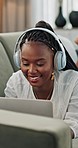 Music, headphones and black woman on laptop on sofa in home, listen to audio or sound to relax. Smile, radio and African person on computer on couch, streaming song online or typing on internet tech