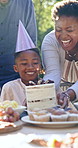 Birthday, black family and child with cake in park for celebration, party and candles for wishing. Food, sparkles and mother, father and kid with dessert for festive event, singing and happy outdoors
