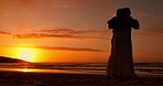 Couple, silhouette and hug at beach, sunset sky and nature for love, romance and bonding on honeymoon. Man, woman and embrace outdoor at dusk, ocean and care with kindness, holiday or summer sunshine