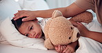 Mother, sick child in bed with teddy bear with cold or flu in home, sad and tired with care, woman and kid. Fever, mom and girl in bedroom with fluffy toy for comfort, healthcare and support in house