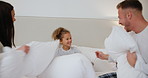 Bedroom, pillow fight and girl with parents playing for love, bonding and loving relationship. Family, home and happy mother, father and young girl with pillows for playful, games and relax on bed