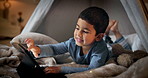 Tablet, games and a boy in a tent the bedroom of his home for education, learning or child development. Smile, technology and relax with a happy young child on the floor for fun in an apartment