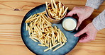 Fast food, french fries and plate with dip at restaurant for chips, potato or dish with sauce. Top view of person serving salted carbs for meal, snack or fresh crispy cut cuisine on table for dining