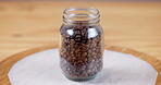 Coffee, beans and closeup on jar container for storage in cafe, kitchen or caffeine in morning. Roasted, blend and ingredient for espresso in glass, bottle or packaging for bistro and restaurant