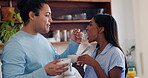 Couple, feeding and happy in kitchen food for romance connection, breakfast fruit or wellness partnership. Man, woman and spoon in taste cereal or love cooking, nutrition smile diet or hungry helping