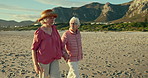 Senior women, walk and holding hands at beach for talk, love or vacation for care, summer or freedom. People, retirement and friends with chat in nature, holiday or relax outdoor for memory in Naples