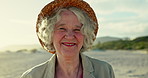 Senior woman, face and vacation on beach, smile and freedom on sand or relaxing on holiday. Elderly person, hat and happy in portrait or confident in retirement, nature and traveling in outdoors