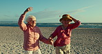 Beach, friends and holding hands with senior women, fun or retirement with adventure, sand or peace. Happiness, outdoor or elderly people with holiday, seaside or ocean with wellness, wind or walking