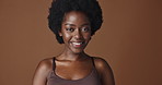 Face, beauty and aesthetic with afro black woman in studio isolated on brown background for wellness. Portrait, smile and happy for skincare, foundation or dermatology with a natural young person