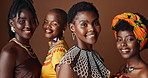 Fashion, beauty and culture with group of black women in studio on brown background together for support. Portrait, smile and heritage with happy African people in clothes of tradition for community