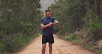 Man, running or smart watch in forest for outdoor fitness, cardiovascular results and performance in nature. Runner, sports gear and check timer, stopwatch clock or exercise progress on path in woods