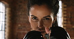 Strong young woman focused on the punching bag at the gym. Powerful athletic woman hitting a punching bag during her boxing workout routine. Fit woman training her arms during cardio boxing routine