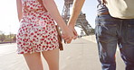 Closeup of a couple holding hands and walking to the Eiffel Tower