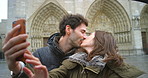 A young couple in love kissing during a selfie taken on a mobile phone