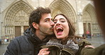A couple in love kissing and taking a selfie in front of Notre Dame