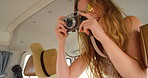 Cheerful woman laughing playfully while taking photos on her camera during a roadtrip