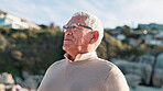 Senior man, thinking and relax on beach by mountain, breathe and peace on summer vacation. Mature person, pension and retirement with travel adventure by blue sky and sunset view on trip by seaside