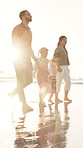 Beach, walking and family holding hands, happiness or ocean with weekend break or vacation. Parents, mother or father with summer or seaside with holiday, lens flare or bonding together with children