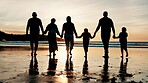 Back, holding hands and silhouette of family walking on beach together for travel, holiday or vacation. Kids, parents and grandparents by ocean or sea for love, adventure or bonding at sunset