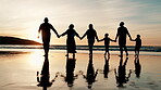 Rear view, holding hands and silhouette of family walking on beach together for travel, holiday or vacation. Kids, parents and grandparents by water or sea for love, adventure or bonding at sunset