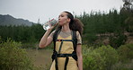 Hiking woman, drinking water and bottle in forest for hydration, detox or wellness on bush adventure. Girl, trekking and liquid for health in nature, woods and outdoor for fitness, exercise or summer