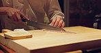 Sushi chef hands, fish and knife for meal prep on table at diner, cuisine and cooking in night. Person, kitchen and restaurant with cutting, ready and services for nutrition, diet and snack in Tokyo