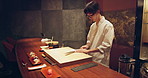 Sushi, food and chef at restaurant cooking on table at diner or cuisine with ingredients at night. Kitchen, fish and culinary artist preparing gourmet Japanese meal or snack with fish at catering job