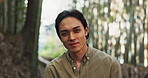 Face, portrait or Asian man in forest for on holiday vacation for freedom or wellness in nature. Fresh air, travel or happy Japanese person with smile for calm, peace and inspiration to relax in park