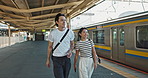 Walking, conversation and young couple by train station for exploring on vacation or holiday. Travel, happy and Asian man and woman talking by public transport for adventure together on weekend trip.