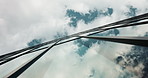 Low angle, skyscraper building and clouds in city with reflection, nature and urban infrastructure. Architecture, cityscape and skyline and metro with landscape, glass and sky background in timelapse