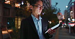 Tablet, night and Asian businessman in the city reading a blog on a website or internet. Online, glasses and young professional male person networking on digital technology in urban town street.
