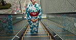 Japanese woman, culture and kimono in town, escalator ride and wellness for heritage celebration. Young person, relax and traditional clothes in tokyo in city, calm and pride for fashion in outdoor