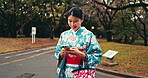 Nature, phone and Japanese woman in a park networking on social media, mobile app or the internet. Travel, field and female person researching on cellphone in an outdoor garden in Tokyo for Autumn.